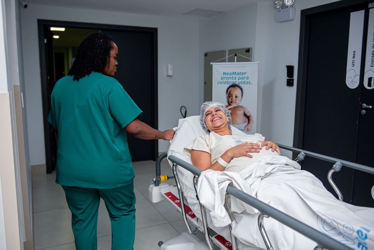 Enfermeira auxiliando paciente com atenção em corredor de hospital, ilustrando a rotina do técnico de enfermagem